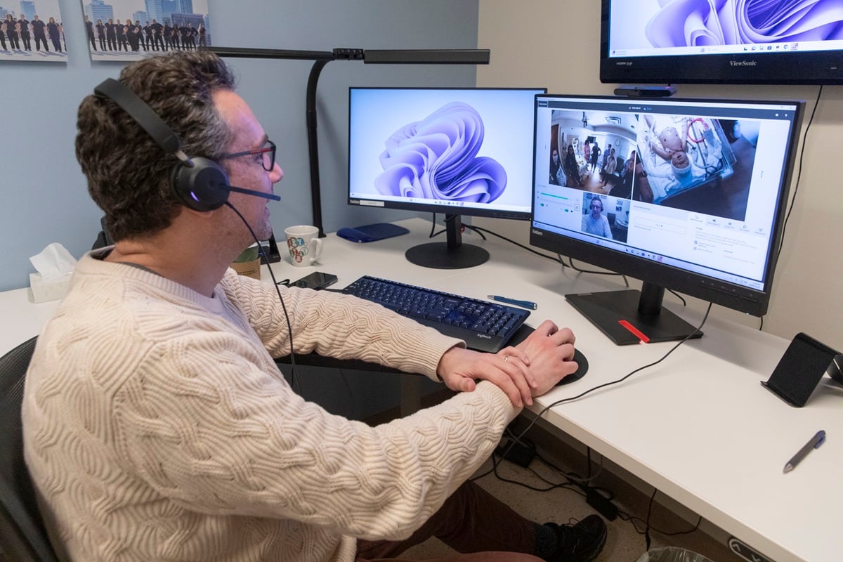 SickKids staff member wearing a headset looks at a screen with a baby mannequin during simulation session.