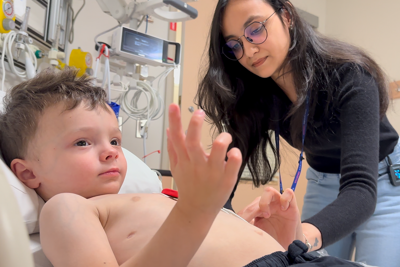 A Clinical Research Associate works with a young boy in a clinical trial at SickKids.
