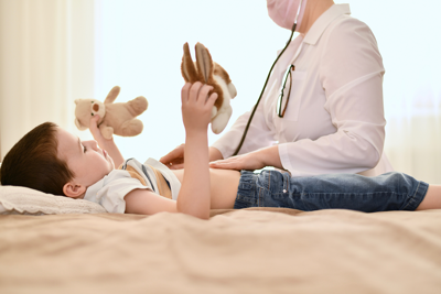 A young boy lies on an examination table beside a doctor.
