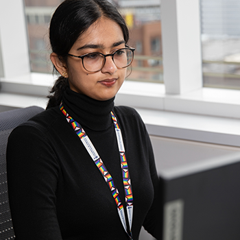 A women sits at a computer desk in a Research Institute.