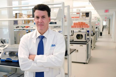 A researcher in a white lab coat standing in a laboratory with scientific equipment.