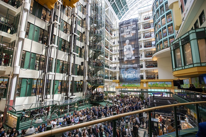 Atrium of hospital filled with people sitting in chairs watching a speaker