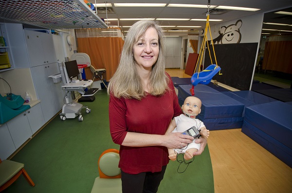 Woman holds infant doll in a therapy room.