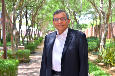 Dr. Zulfiqar Bhutta stands outside on a tree-lined path.