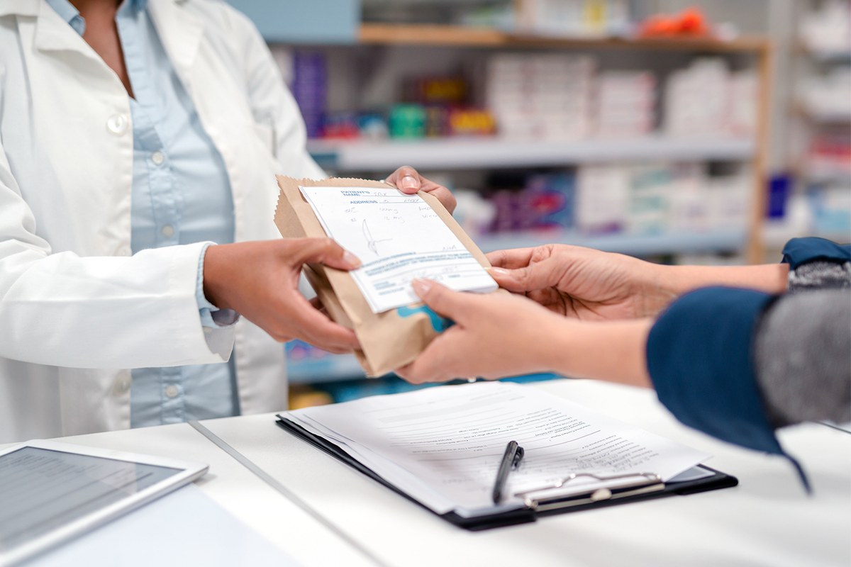 A pharmacists hands a person a prescription.