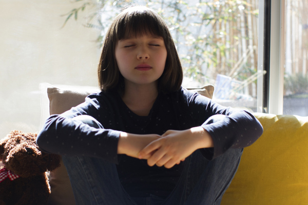 Teen with eyes closed practicing mindfulness while relaxed on a chair