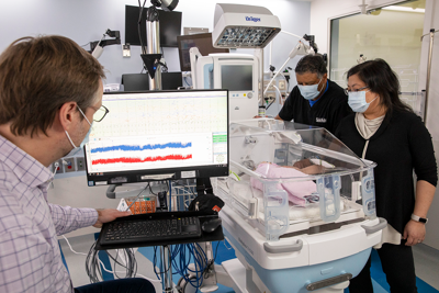 SickKids physicians and EEG technicians gather around an infant in the neonatal intensive care unit to monitor the child’s brain activity.