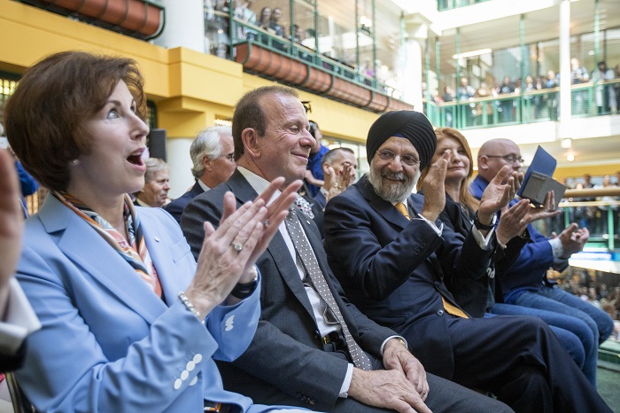 Katie Taylor, Sabi Marwah and Peter Gilgan sit next to each other in chairs smiling