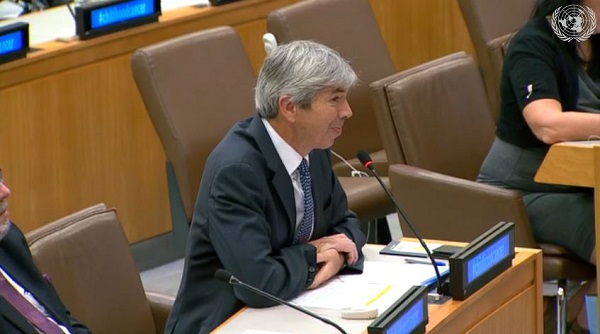 Man sits at desk speaking in a microphone.