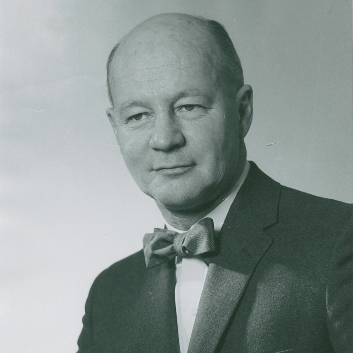 Portrait photograph of Dr. William Mustard in a suit with bow tie, who pioneered the 'Mustard procedure' in 1963 to correct Blue Baby Syndrome.