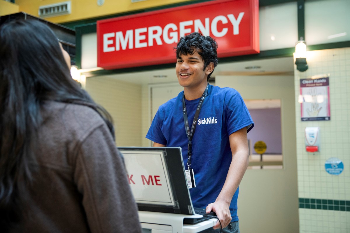 Volunteer at computer kiosk outside Emergency Department.