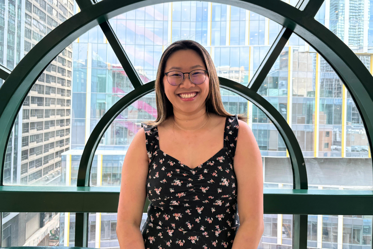 Crystal Mui stands smiling in front of windows in the SickKids atrium