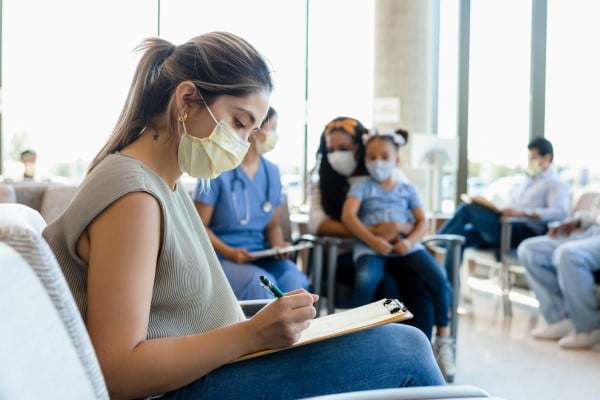 Woman sits in a hospital waiting room filling out an admission form