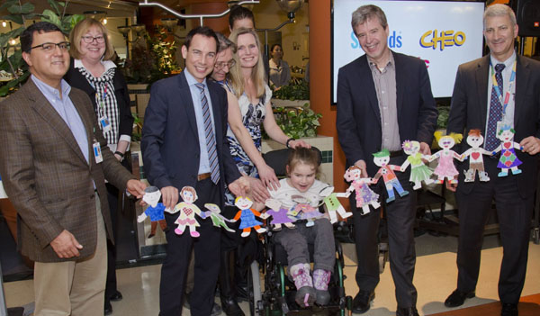 Group of people hold up a children's craft which is a chain of people.