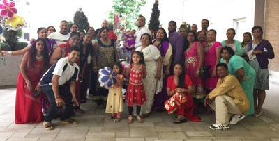 Large group photo of approximately 30 children and adults wearing brightly coloured clothes.