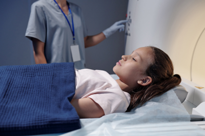 Child lays on a CT bed.