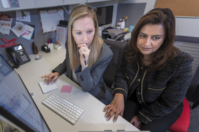Two people sitting at a desk working on a computer.