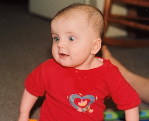 Liv, six months old, in a red shirt with a heart on it.