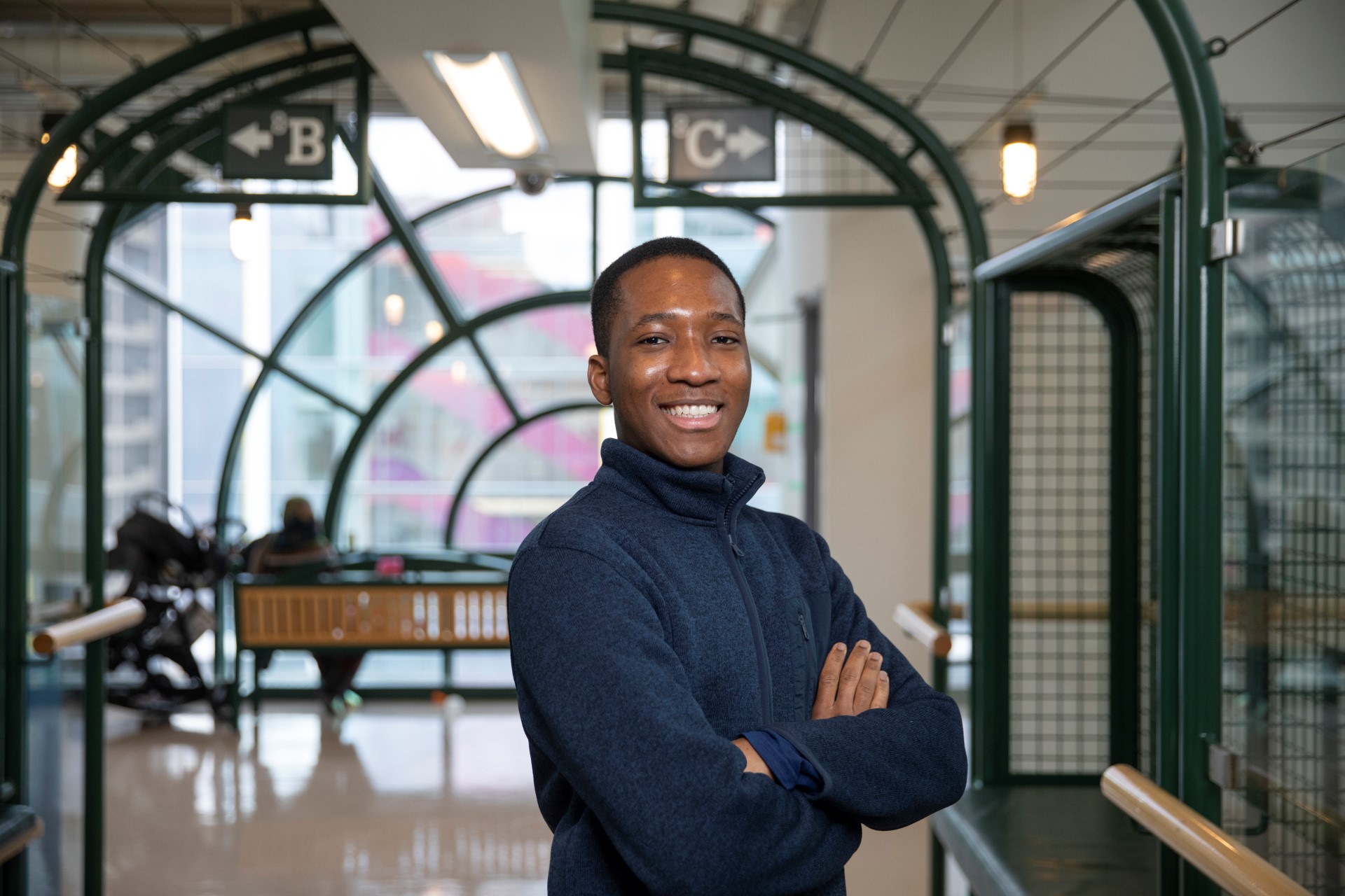 James, wearing a navy blue sweater, stands in the hallway with signs for units 8B and 8C behind him.