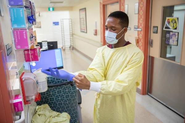Wearing a yellow gown and mask, James puts on gloves.